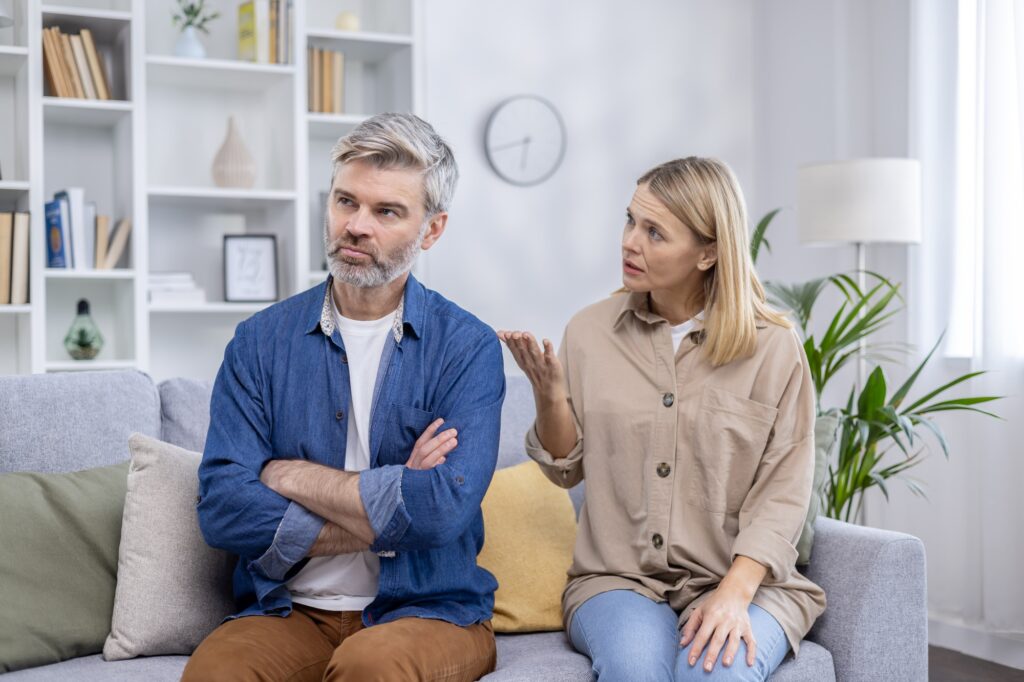Mature couple discussing issues at home with serious expressions